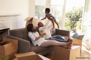 Family with toddler resting on a couch amidst moving boxes