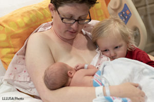 Mother tandem nursing her newborn and toddler in the hospital