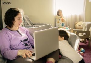 Mom working on laptop with kids playing