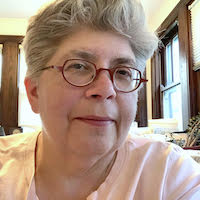 White person with short grey hair and glasses is looking at the camera.